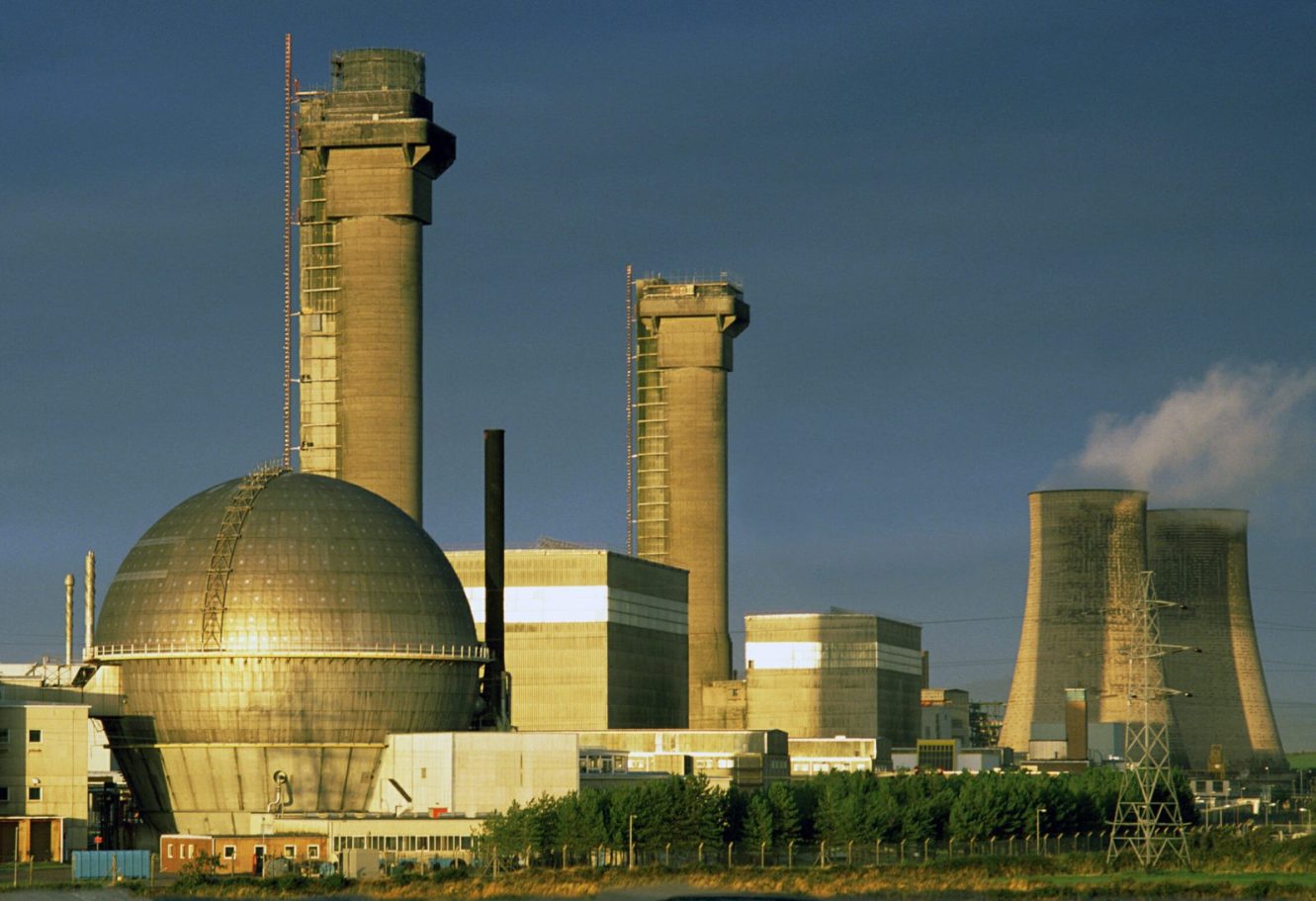 Industrial power plant with cooling towers and large spherical structures under a blue sky.