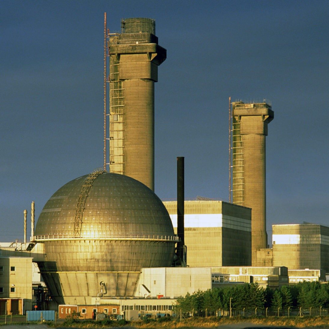 Industrial power plant with prominent smokestacks and a large spherical structure.